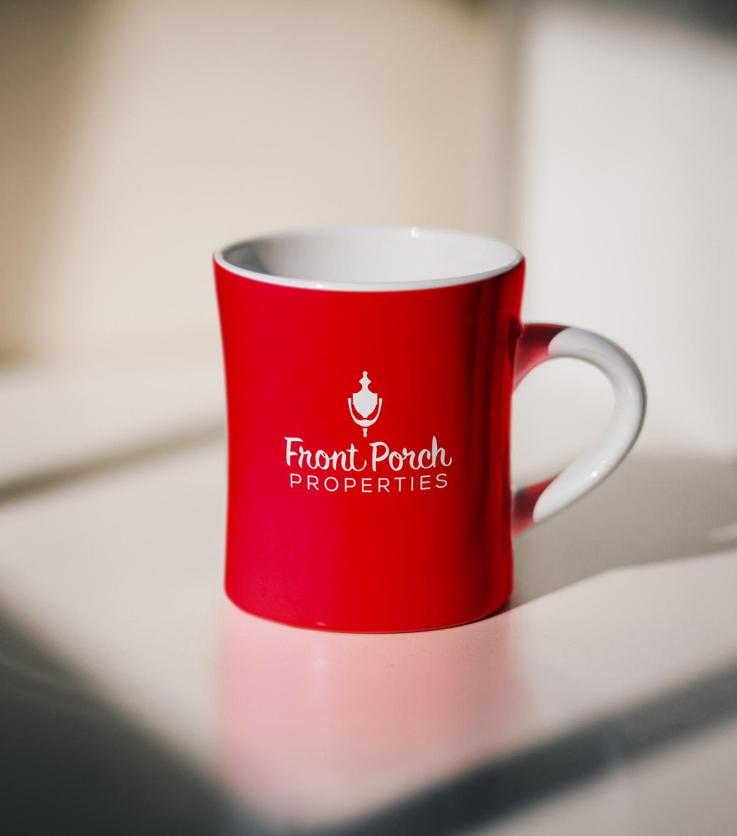 A red coffee mug with a white Front Porch Logo